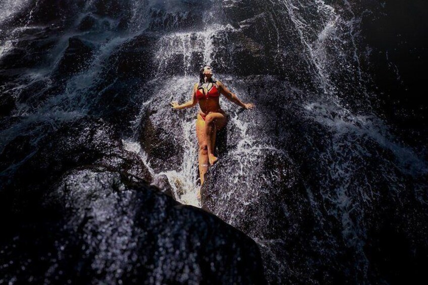 A person standing on a rock in a waterfall. 5