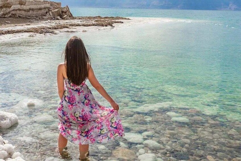 A person standing by a clear, shallow body of water with rocks and a rocky shoreline. 5