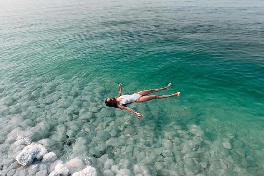 A person floating on water with clear rocks beneath. 4