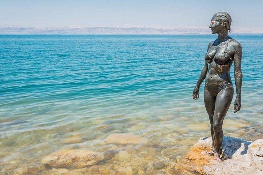 A statue of a woman in a swimsuit standing in shallow water with a clear blue sea in the background. 4