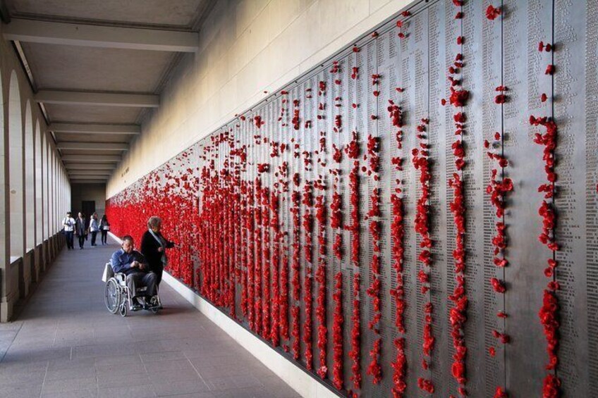 A memorial wall with red flowers and a person in a wheelchair. 5