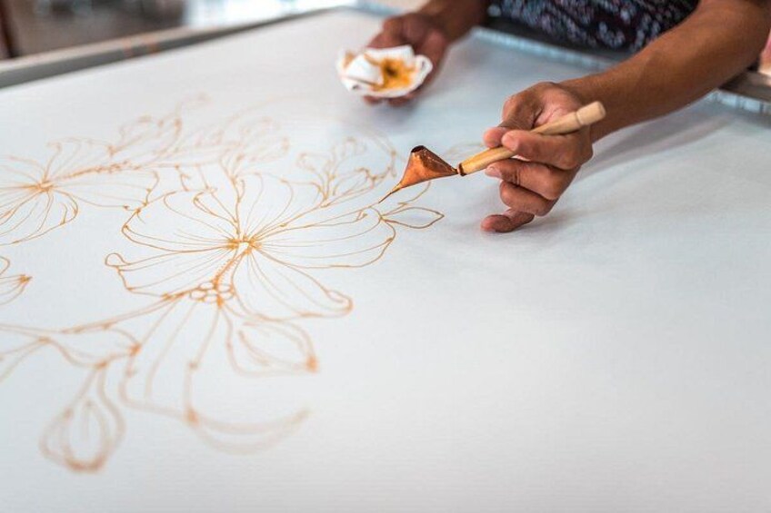 A person drawing floral patterns on a large white surface with a brush. 5