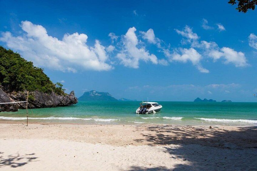 A beach with a boat on the water, a clear sky, and distant mountains. 5