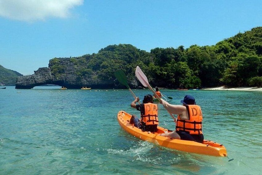 Two people kayaking on clear water with a rocky island in the background. 4