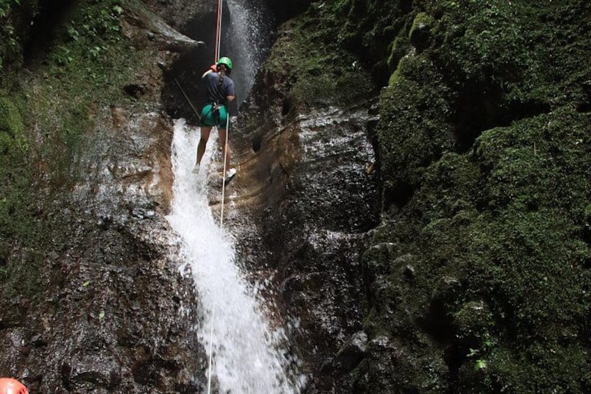 A person rappelling down a rocky cliff with a rope. 5