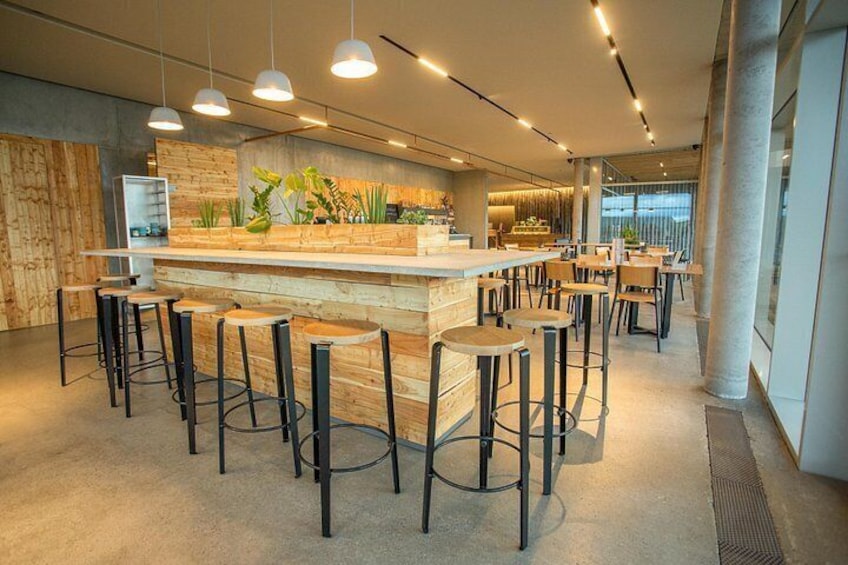 Un espace bar moderne agrémenté d’éléments en bois, de tabourets de bar et d’un éclairage suspendu. 3