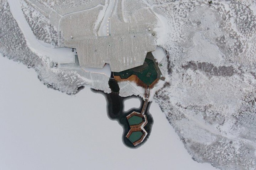 Vue aérienne d’un paysage enneigé, avec une structure hexagonale et un bâtiment rectangulaire. 4