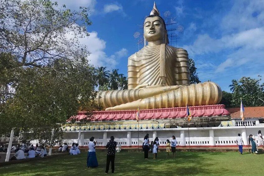 Une grande statue de Bouddha en or, avec un temple à toit blanc en arrière-plan. 5