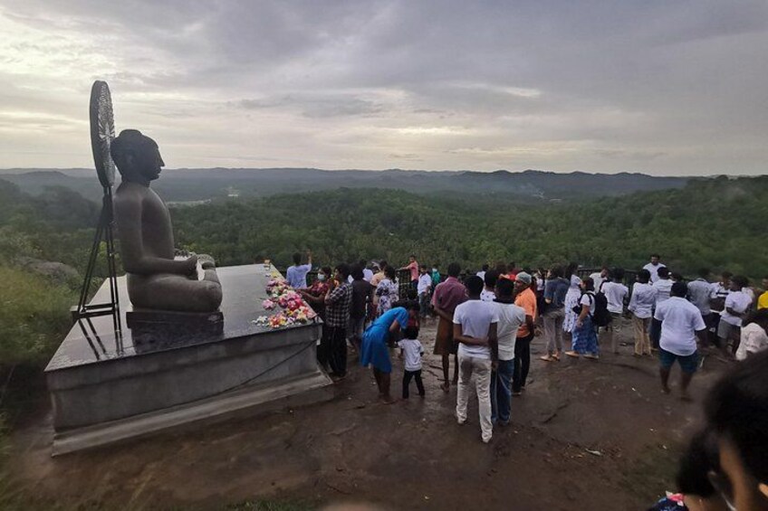 Une grande statue de Bouddha, placée sur un piédestal, est entourée d’une foule de personnes. 4