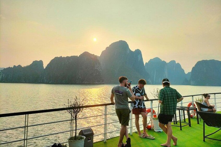 A group of people on a boat deck overlooking a body of water with distant mountains. 3