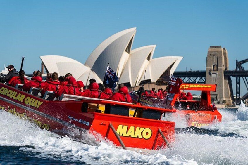 Two red speedboats with passengers, one with a flag, in Sydney Harbour with the Sydney Opera House in the background. 2