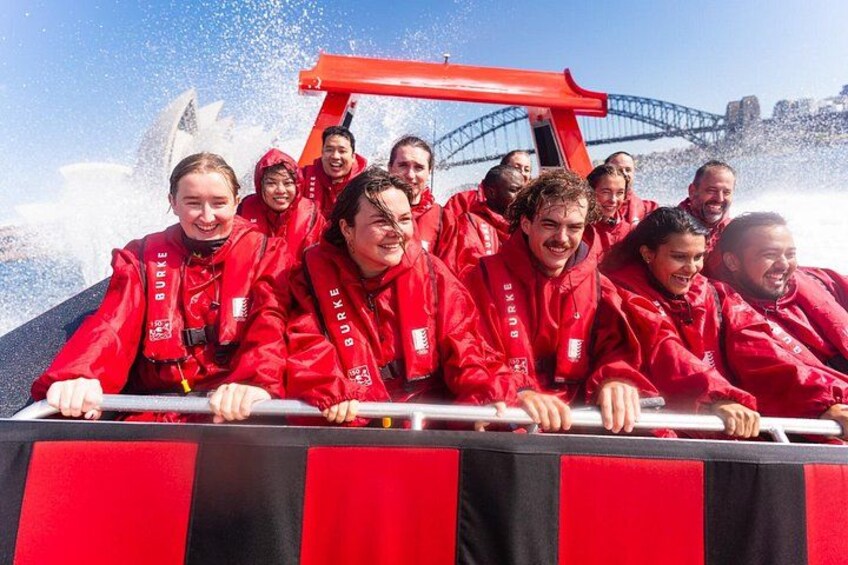 A group of people in red jackets on a boat with a red structure in the background. 1