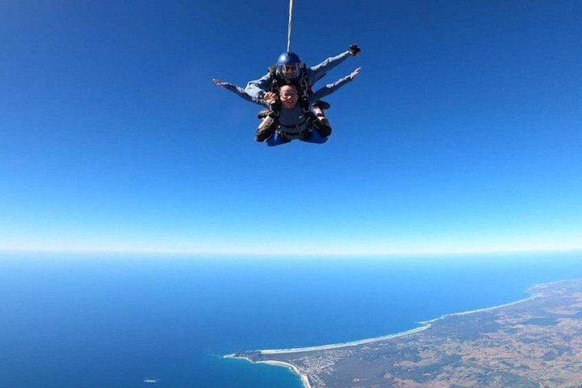 A person skydiving with a parachute above a coastal landscape. 2