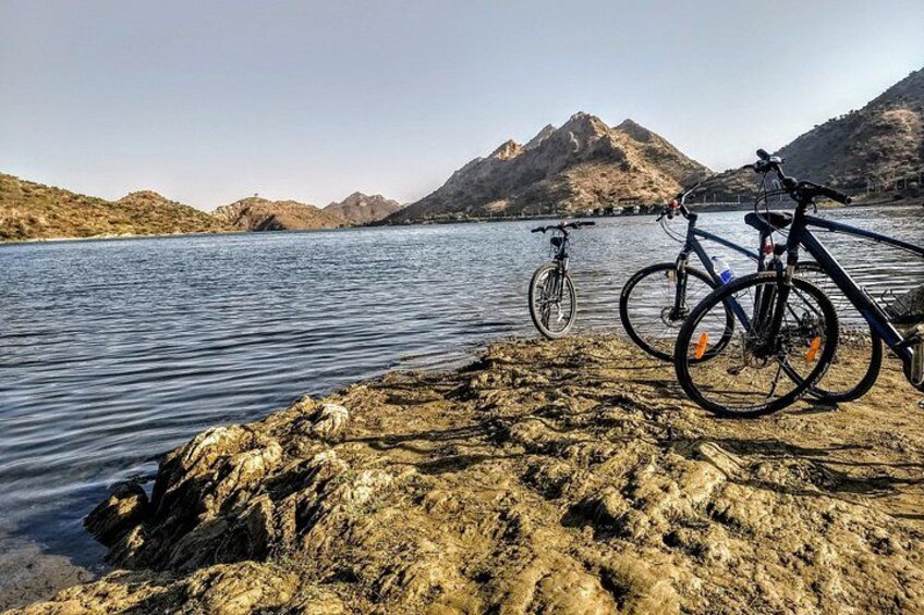 Un rivage rocheux avec deux vélos, un lac et des montagnes en arrière-plan. 1