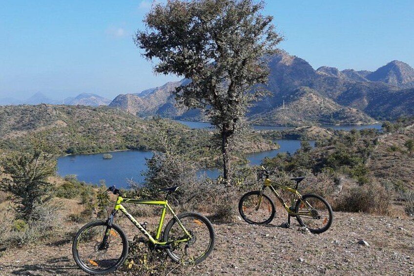 Deux vélos sont garés sur un chemin de terre, avec un lac et des montagnes en arrière-plan. 2
