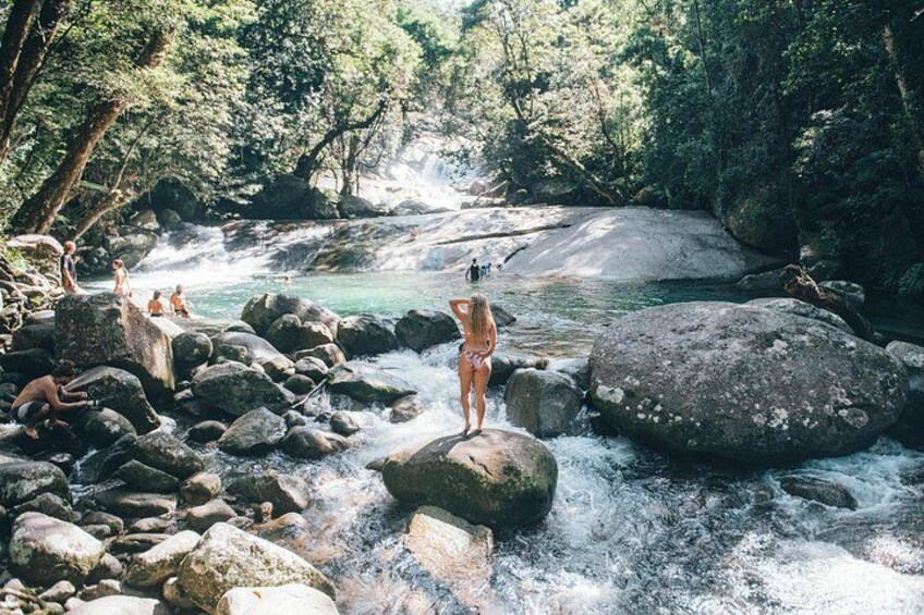 Une rivière avec des rochers, une cascade et des gens qui se baignent. 3