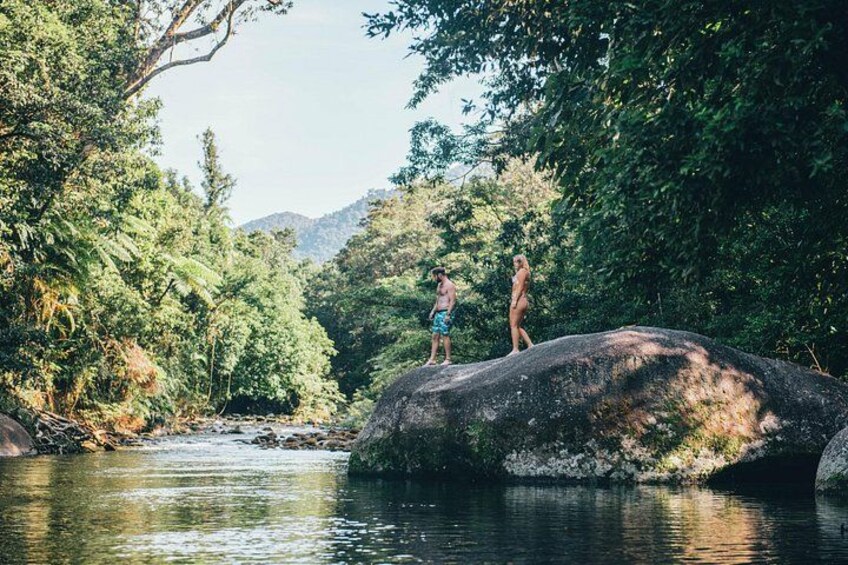 Due persone in piedi su una roccia vicino a un fiume, circondate da vegetazione fitta. 2