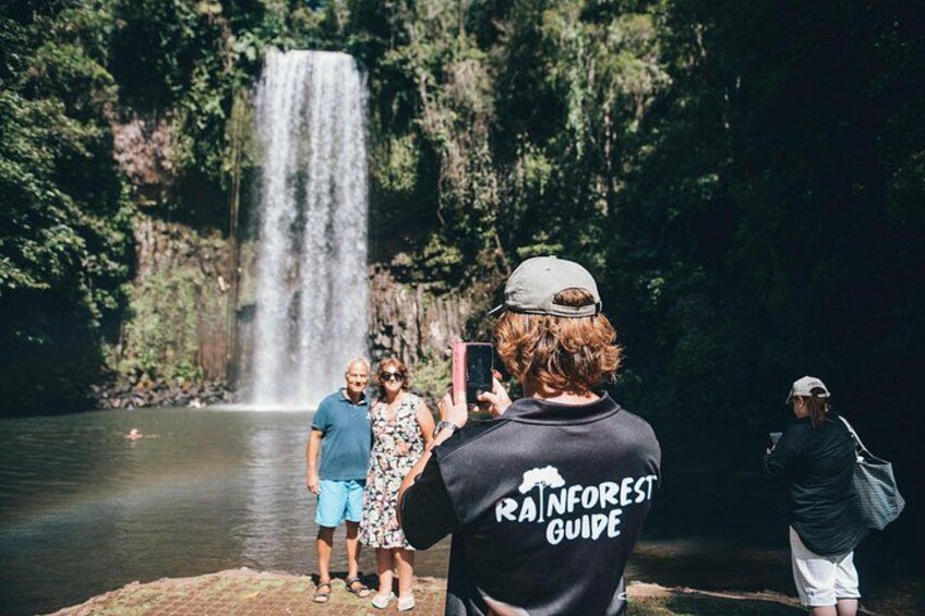 A waterfall, a person taking a photo, and a group of people standing by the water. 3