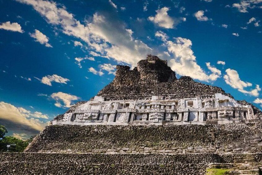 Una gran pirámide con intrincados grabados, sobre un cielo azul con algunas nubes dispersas. 2