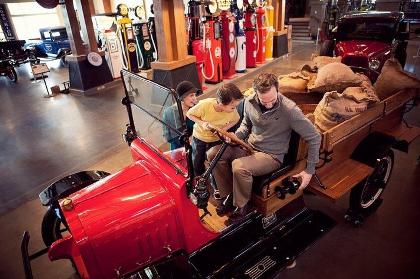 A vintage truck with a red front, a wooden cart attached, and a person driving. 2