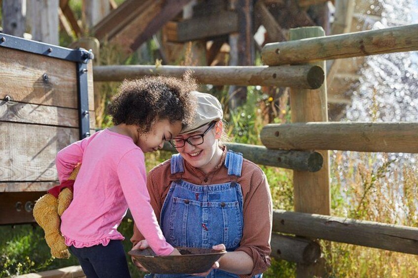 Two people near a wooden structure with a child holding a stuffed animal. 5