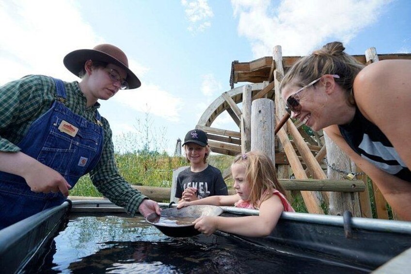 A group of people at a water treatment facility with a large wooden wheel structure in the background. 3