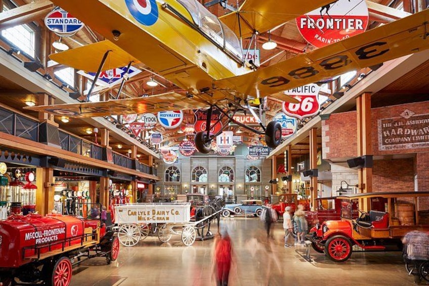 Un marché intérieur à la décoration d’époque, avec des voitures anciennes, un attelage tiré par des chevaux et des enseignes suspendues. 1