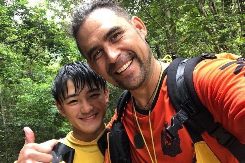 A person wearing a backpack and a yellow shirt, with a forested background. 3