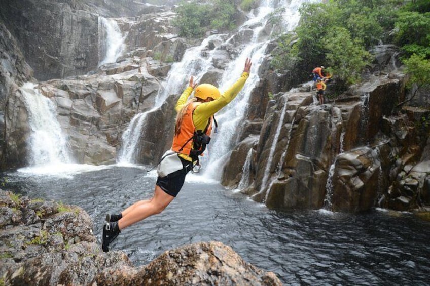 Una persona saltando desde una roca hacia una cascada. 1