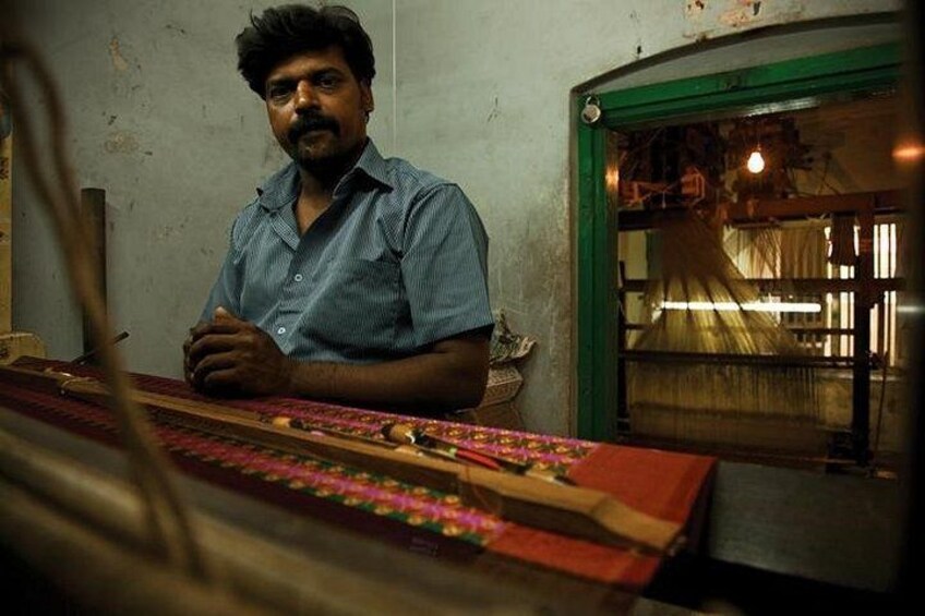 A person sitting at a table with a loom, suggesting textile work. 4