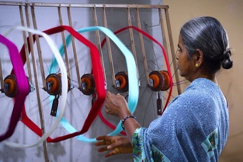 A person operating a spinning wheel with multiple spools of thread. 2