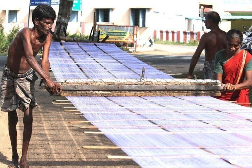 People handling large sheets of material, possibly for construction or repair work, outdoors. 3