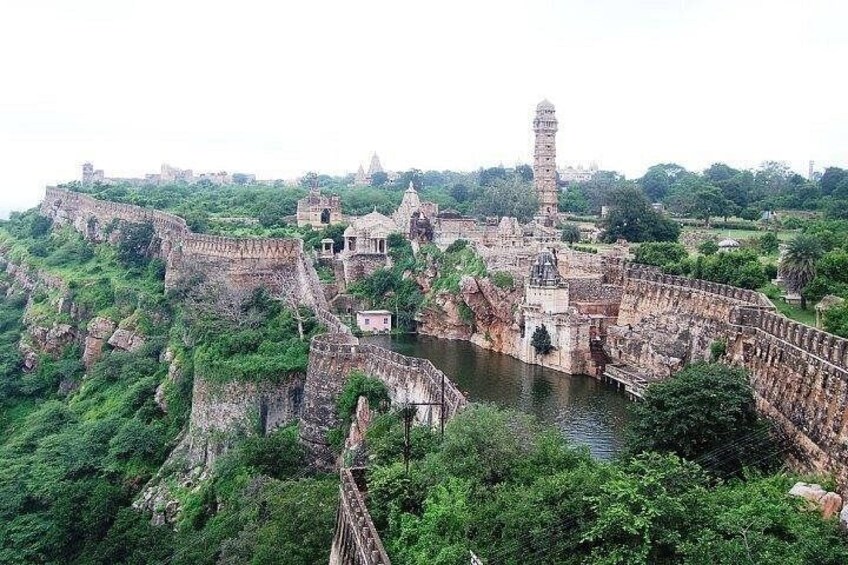 An ancient fort with a watchtower, surrounded by lush greenery and a river. 1