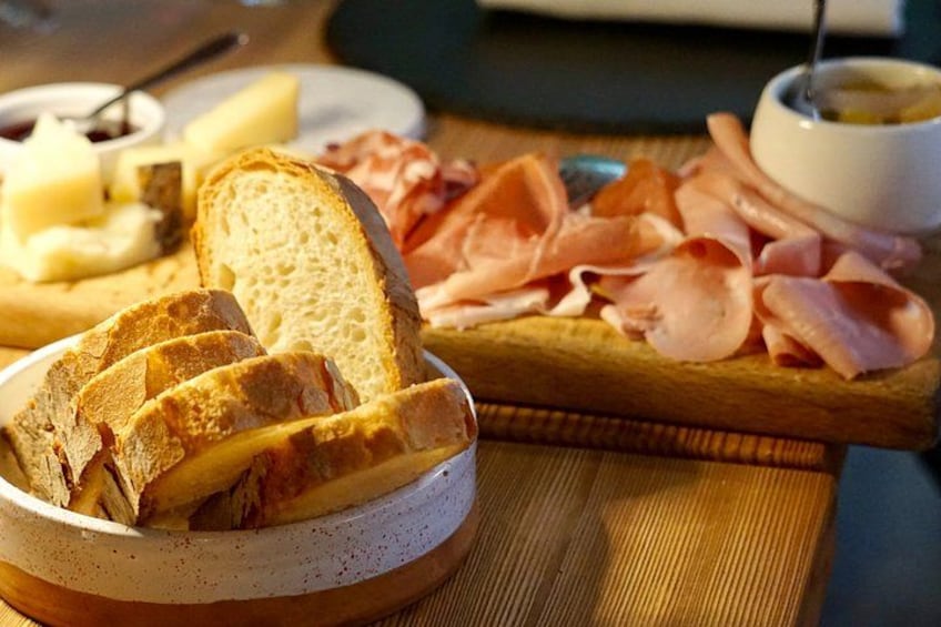 Une planche de charcuterie accompagnée de pain, de fromage et de différentes sortes de viandes. 5