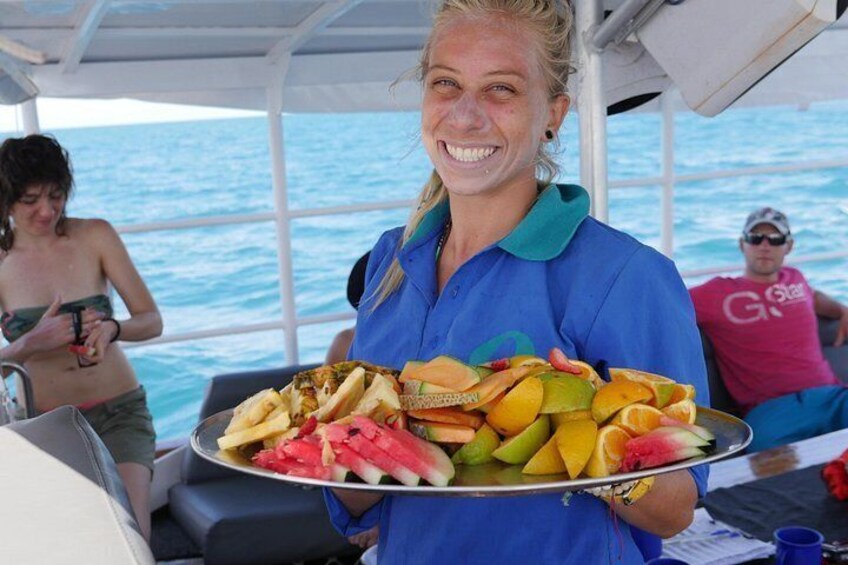 A person holding a tray of fruits on a boat. 2