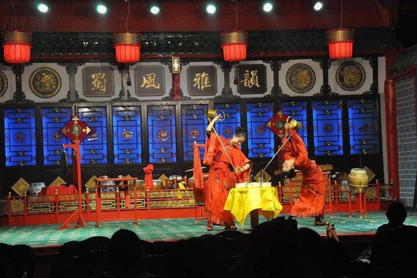 A stage with performers in red robes, a yellow table, and traditional Chinese decorations. 4