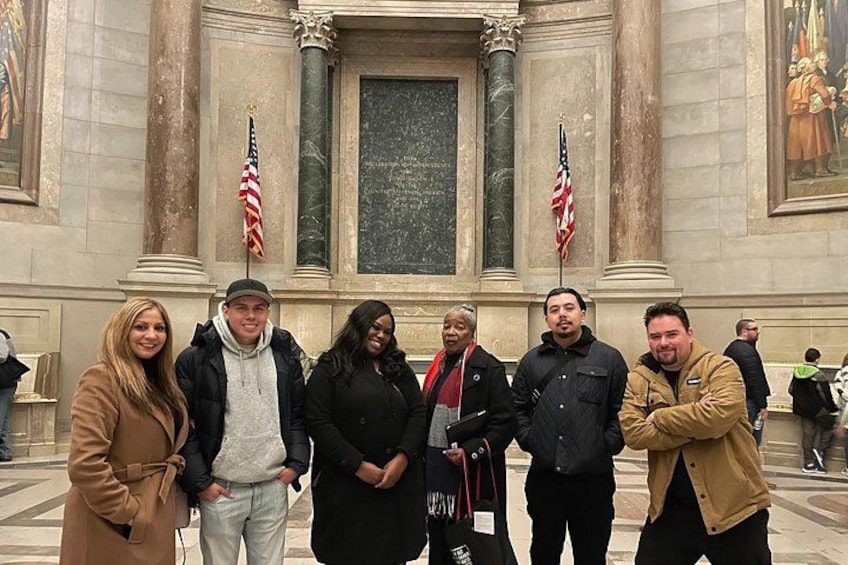 A group of people standing in front of a building with columns and American flags. 2