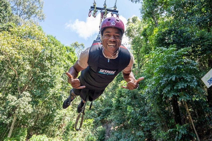 A person bungee jumping with a harness and helmet, surrounded by dense green foliage. 5