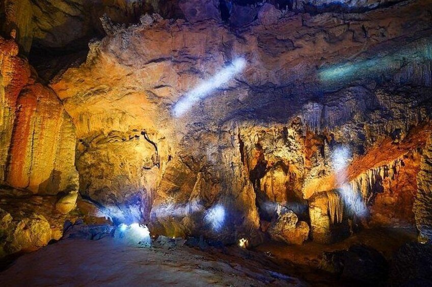 A cave with stalactites and stalagmites illuminated by artificial lighting. 1