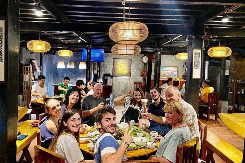 A group of people dining in a restaurant with wooden tables and hanging light fixtures. 5