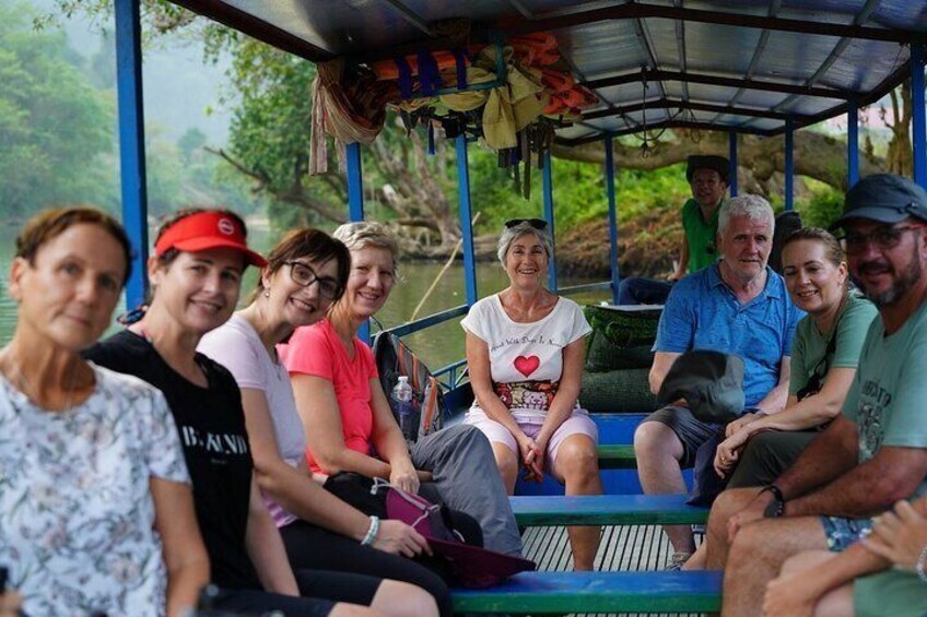 A group of people sitting on a boat with a covered structure. 2