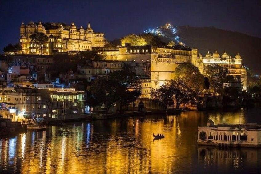 A nighttime view of a historic palace complex with illuminated buildings reflecting on the water. 3