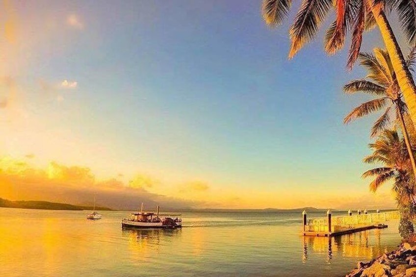 Un lago tranquilo con un bote, un muelle y palmeras al atardecer. 5