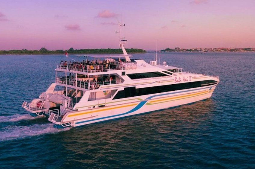A large white and yellow cruise ship named 'Bali Hai' with passengers on deck, sailing on calm waters. 2