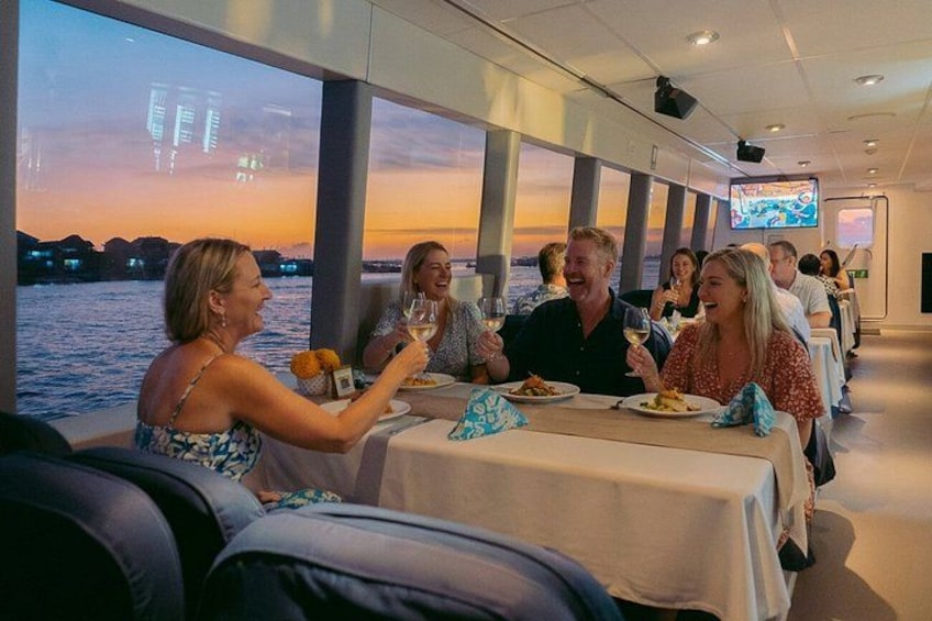 Un groupe de personnes dînant sur un navire de croisière, avec une vue sur le coucher de soleil. 3