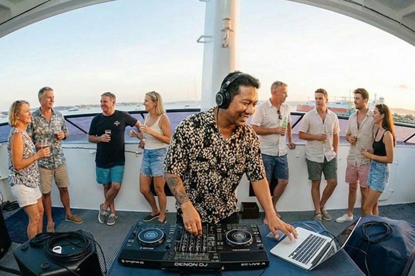 Une personne qui mixe de la musique sur un bateau, à l’aide d’un ordinateur portable et de matériel de DJ. 4