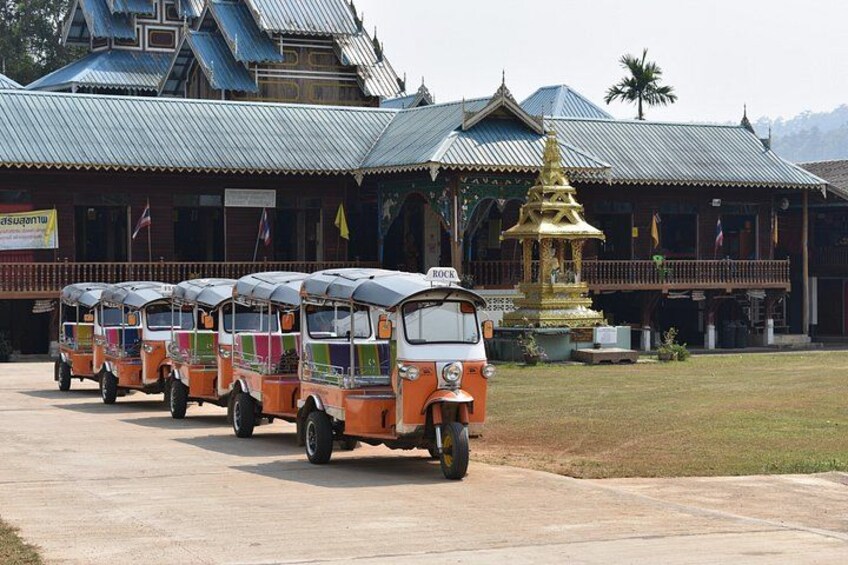 En rad tuk-tuks parkerade framför en traditionell byggnad med en gyllene stupa. 2