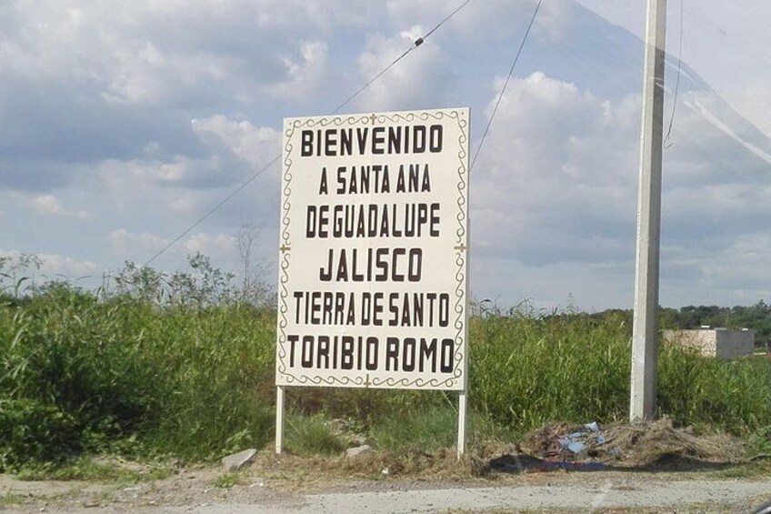 A welcome sign with text in Spanish, surrounded by greenery and a clear sky. 5