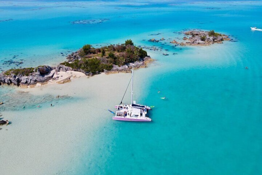 A white sailboat anchored near a small island with clear turquoise waters. 5