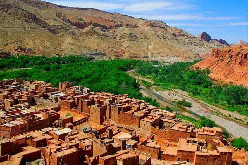 A village with terracotta-roofed buildings nestled in a valley, surrounded by green vegetation and mountains. 4